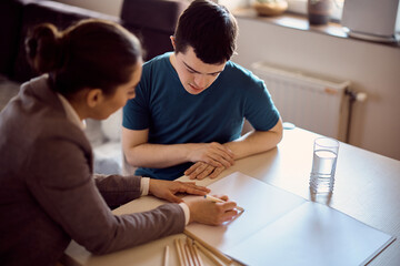 Man with down syndrome having individual education class with is tutor at home.