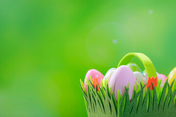 Happy Easter Postcard. Easter eggs in a basket on a green background with space for text. Multi-colored decorated eggs on a spring backdrop.