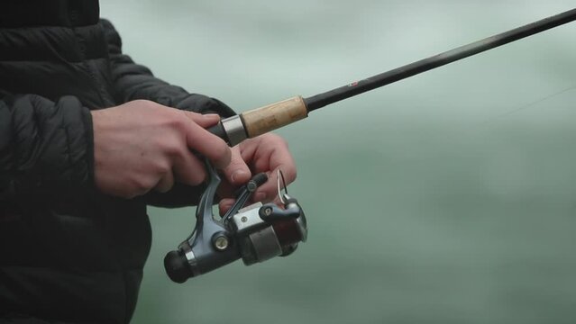 120 fps slow motion close up of a man holding a fishing rod and reel or angler in cold weather. 