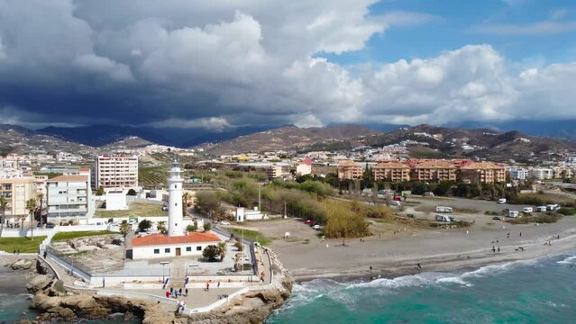 Drone perspective of costal city of Torrox situated in Malaga, Costa del Sol, Spain. Touristic travel destination. View of the promenade and beach area. The lighthouse of Torrox and the river. Back