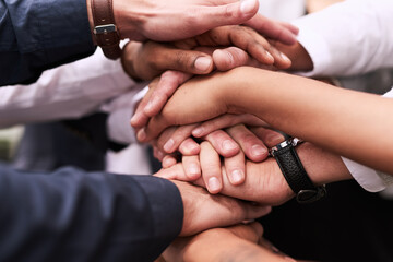 We work better when we get together as one. Closeup shot of an unrecognizable group of businesspeople joining their hands in a huddle.