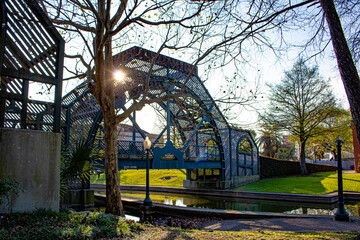 Sunlight Peeks through the Metal Arch of a Bridge Crossing a Stream in the Louis Armstrong Park in New Orleans, Louisiana, USA