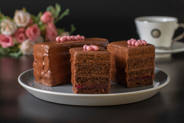 Sliced mousse chocolate desserts with chocolate cream and raspberry marmalade covered gourmet chocolate glaze on a black background