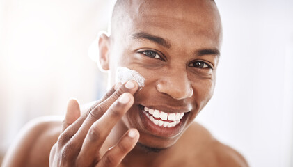 Ladies love a smooth talker with an even smoother face. Portrait of a handsome young man applying moisturizer to his face in the bathroom at home.