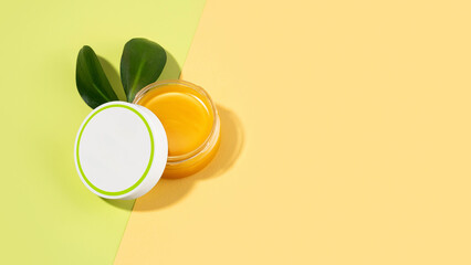 An open tin of foot balm with sheep's wool grease. Lanolin cosmetics for self-care, a jar of waterproofing wax on a light green and beige background. The concept of skin care