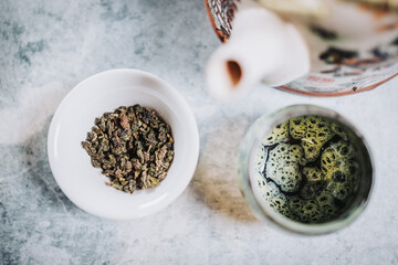 Tea time. Teapot, a cup, and dried tea ready to be served, over a gray backdrop. Infusion.