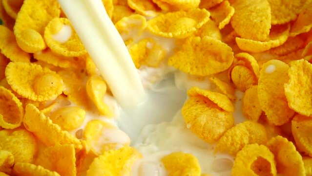 Falling jet of milk into corn natural flakes. Slow