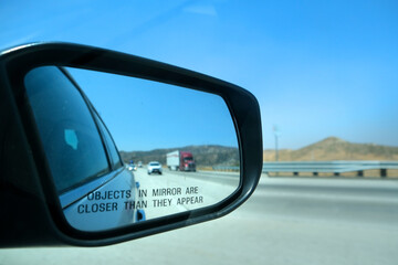 Image through the rearview mirror of a car with the inscription "Objects in mirror are closer than they appeare"