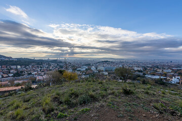 Panorama of Barcelona from the air in the early morning. City with shadows from the clouds. Dramatic sky over the city. Autumn in Barcelona, Spain.