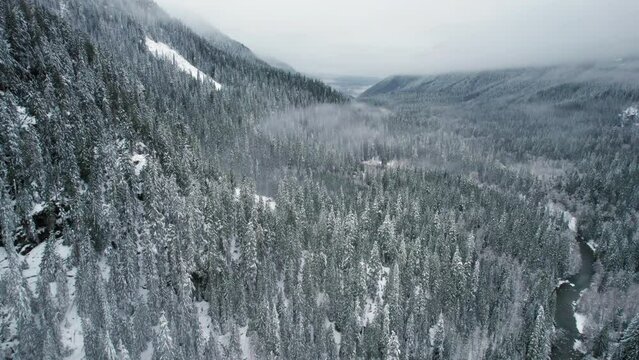 Dramatic Aerial View of Snow Covered Mountain Valley with Lowland Fog Clouds