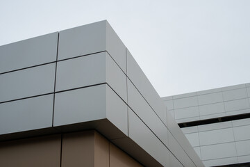 The exterior wall of a contemporary commercial style building with aluminum metal composite panels in three rows. The futuristic building has engineered diagonal cladding steel frame panels.