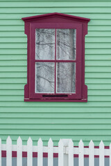 A vibrant lime green exterior wall of narrow horizontal cape cod clapboard on a house. There's a...