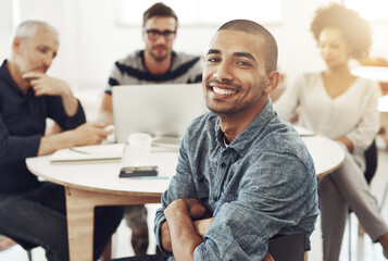 Obraz premium My team is headed for success. Portrait of a young office worker sitting at a table with colleagues in the background.