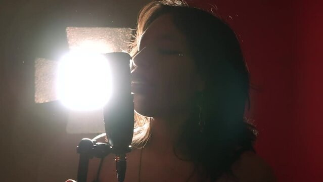 Mujer joven disfrutando del canto. Mujer cantando en estudio.