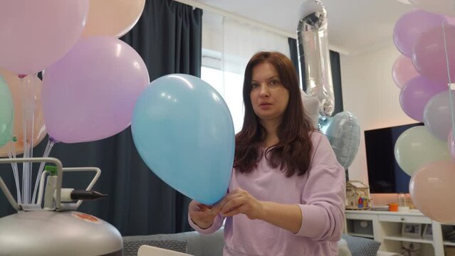 Woman using helium tank blowing up balloons to decorate home for party, colorful balloons for birthday wedding christmas party event decorations. High quality 4k footage