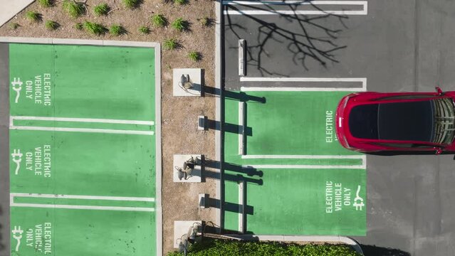 Scenic aerial red electric vehicle parking rear at electric charging station 4k