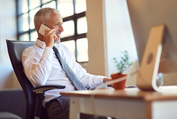 Hes the man everybody wants to talk to. Shot of a mature businessman using his phone in the office.