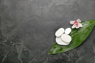 Spa stones with orchid flower and tropical leaf on dark background
