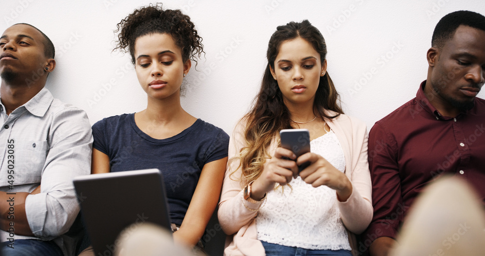 Poster Keeping busy on their devices. Cropped shot of a group of diverse businesspeople waiting in line for an interview.