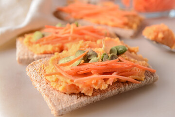 Crispbreads with tasty carrot hummus on white background, closeup