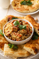 Bowl with tasty Asian pilaf and flatbread on tray