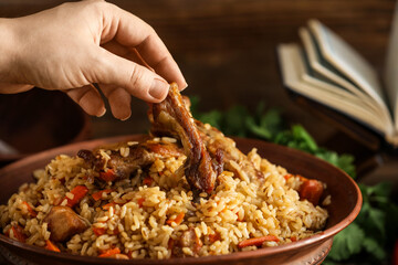Woman eating tasty Asian pilaf from bowl