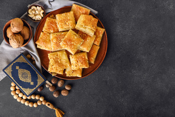 Tasty Turkish baklava and Quran with tasbih on dark background