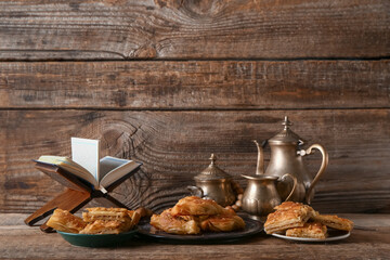 Tasty Turkish baklava with Quran and tea on wooden background