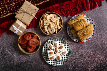Tasty Eastern sweets with gifts on dark background