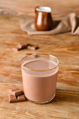 Glass of delicious chocolate milk on wooden background