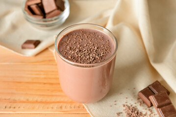 Glass of delicious chocolate milk on wooden background