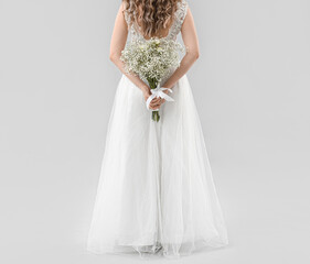 Fototapeta na wymiar Beautiful bride with bouquet of flowers on light background