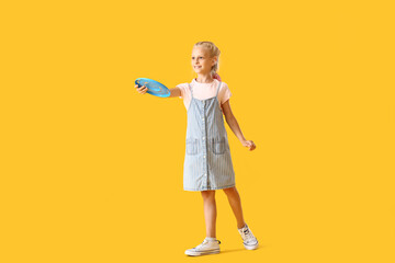 Funny little girl playing frisbee on color background