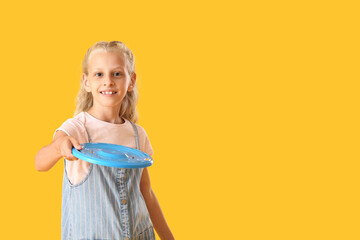 Funny little girl playing frisbee on color background