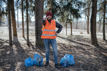 volunteer cleaner is cleaning up park and standing by bunch of garbage