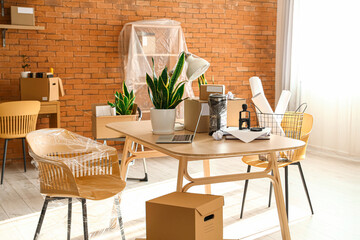 Cardboard boxes with belongings and furniture in interior of office on moving day