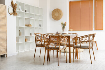 Interior of light dining room with table and shelving unit