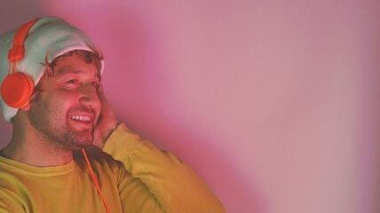 Young man wear yellow shirt headphones listen to music isolated on plain pastel pink color background studio portrait.