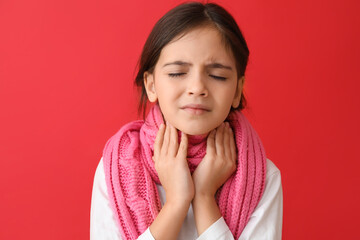 Little girl with scarf suffering from sore throat on red background