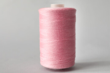Fototapeta na wymiar Pink sewing thread spool on light background