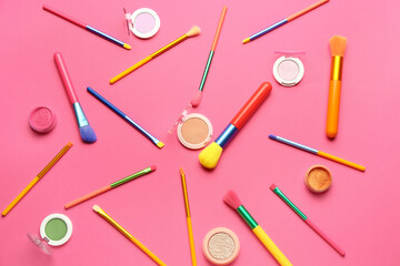 Composition with makeup brushes and different eyeshadows on pink background
