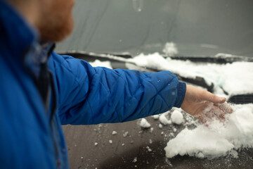 Fototapeta na wymiar Snow removal from car. Hand scrapes ice off car.