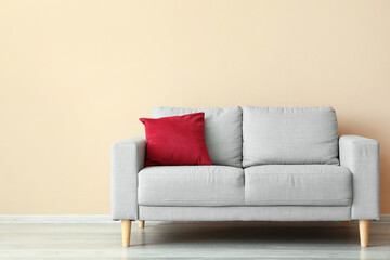 Stylish sofa near beige wall