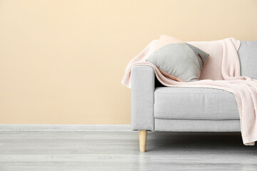 Stylish sofa near beige wall