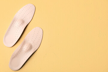 Pair of leather orthopedic insoles on color background