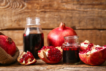 Jars of pomegranate molasses and fresh fruits on wooden background