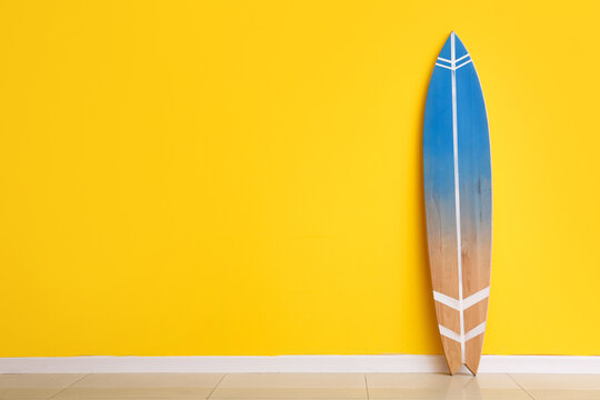 Blue surfboard near yellow wall