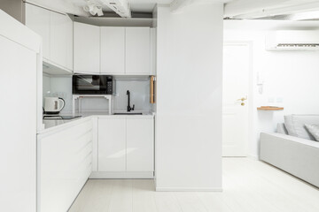 Bright white wood cabinets kitchen with microwave and countertop and sloping ceilings