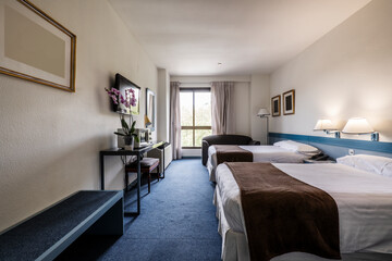 Hotel room with two king size beds, desk with chest, flat screen TV on the wall and blue carpet floors