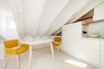 dining table next to white kitchen with wooden shelves in attic apartment